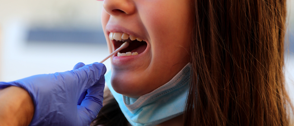 girl getting a COVID-19 test with a mouth swab