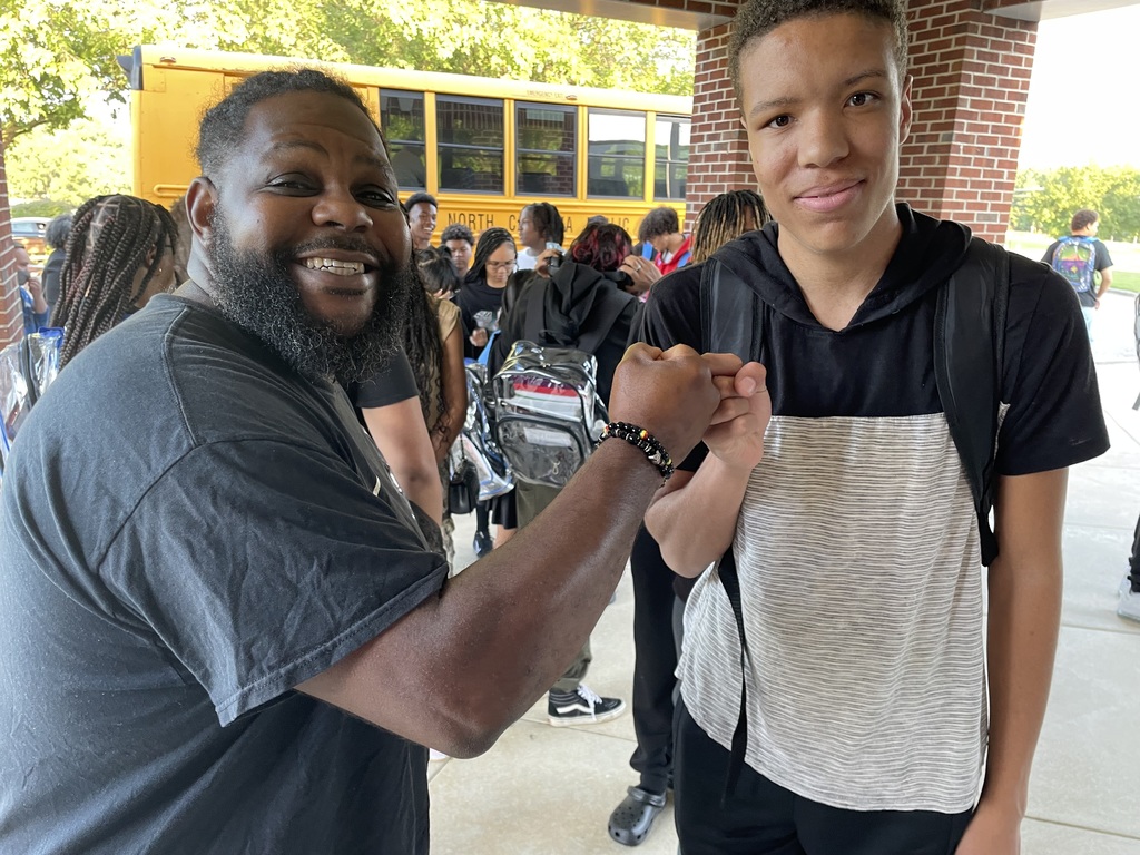 A greeter fist bumps a student at the beginning of the first day of school